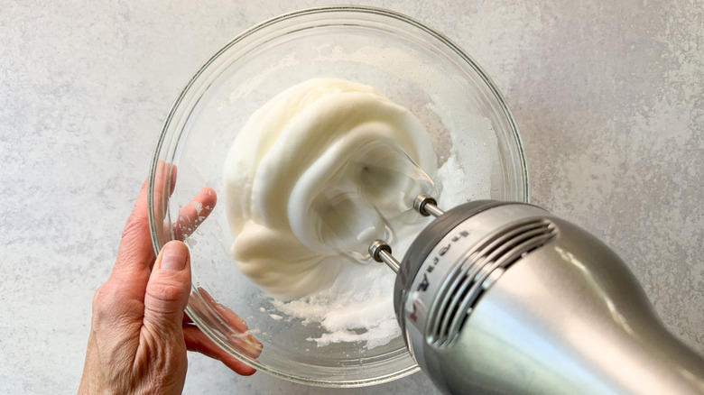 Beating egg whites in a glass mixing bowl with hand mixer