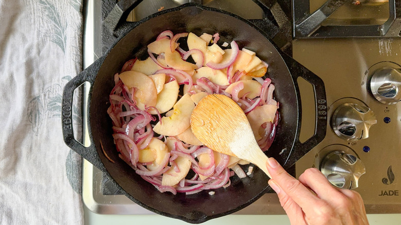 Sauteed apples and onions in cast iron skillet with wooden spoon