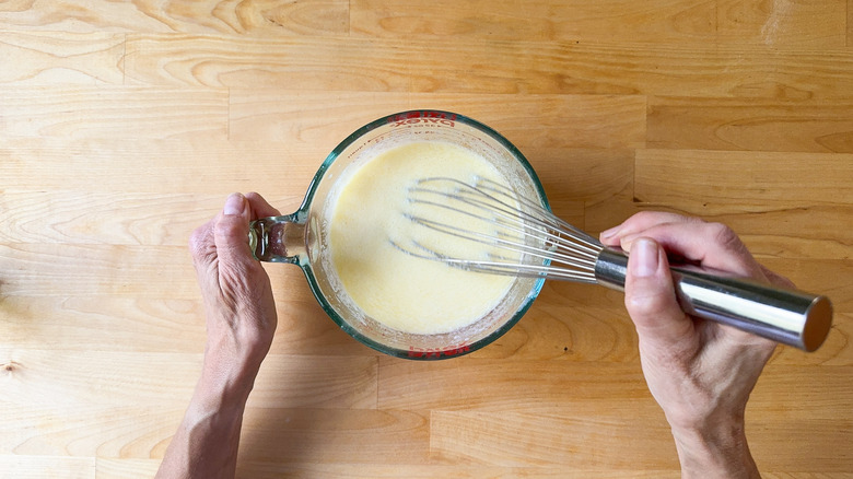 Whisking together cornbread liquid ingredients in large measuring glass