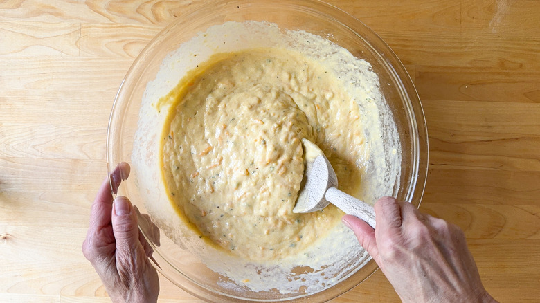 Mixing cornbread batter in glass bowl with wooden spoon