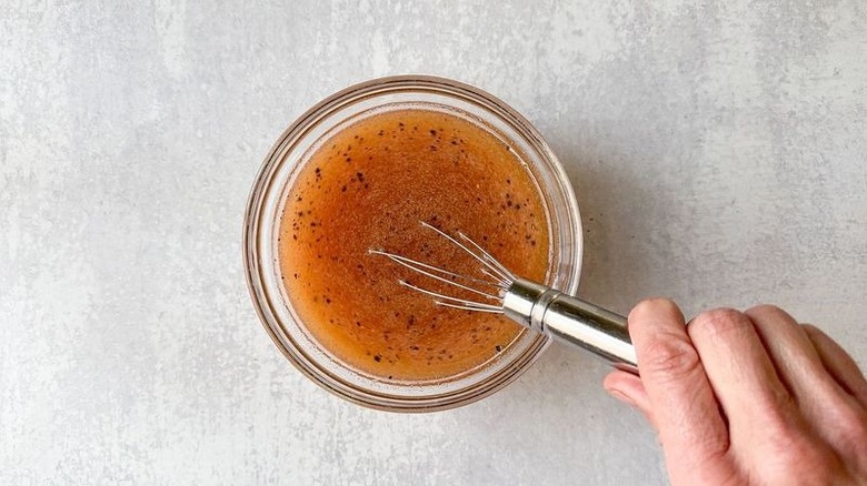 Sweet and spicy Korean fried popcorn chicken brine in glass bowl with whisk