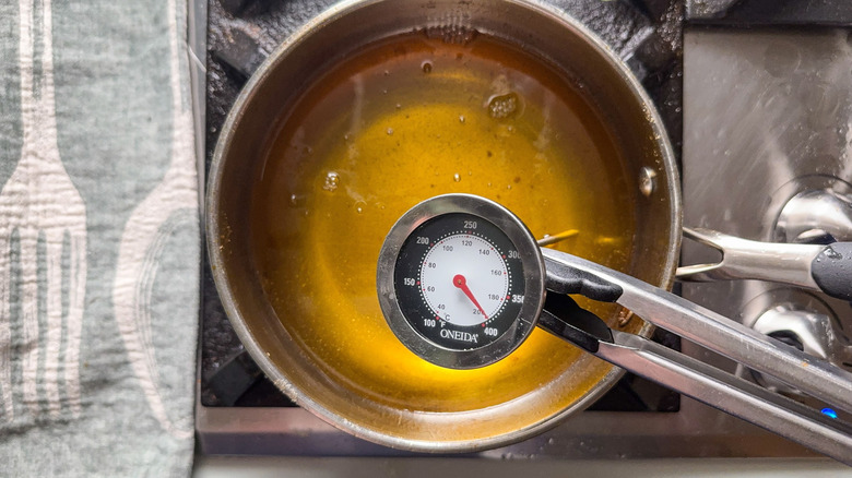 Avocado oil heated to 375 F in pot on stove with thermometer