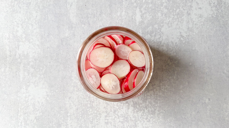 Radish slices in glass jar with pickling liquid
