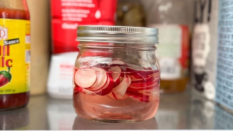 Radish pickles in glass jar in refrigerator