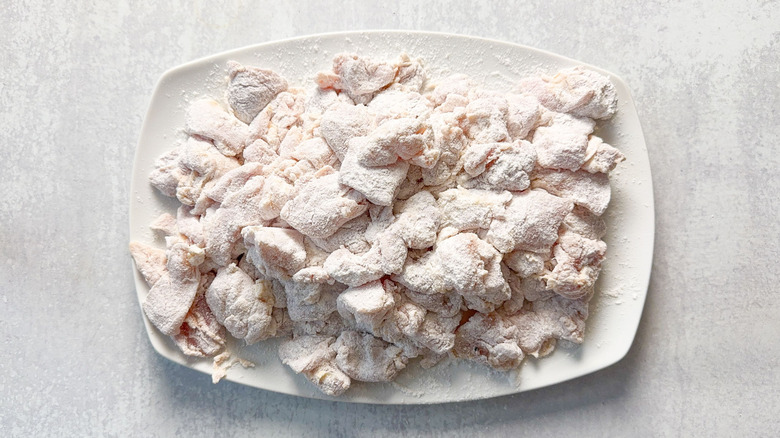 Flour-dusted chicken thigh pieces on platter