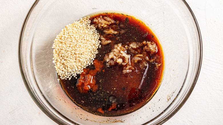 Bowl with soy sauce, minced garlic, and sesame seed