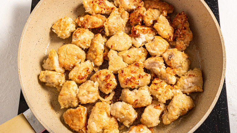 Skillet with breaded crispy chicken pieces