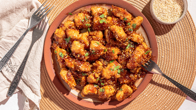 Plate with sweet and spicy sesame chicken with a fork on the side