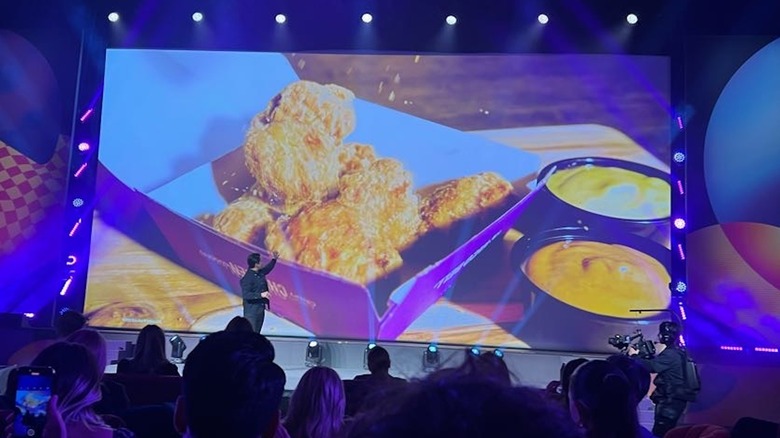 Taco Bell's chicken nuggets pictured on a big screen above a stage at a presentation