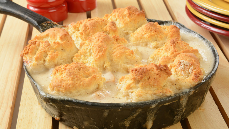 A cast iron pan filled with gravy and biscuits