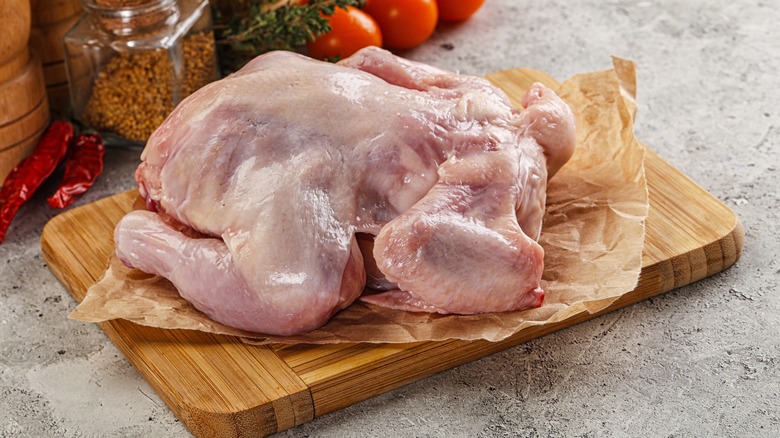 A fresh raw chicken on a wooden board.