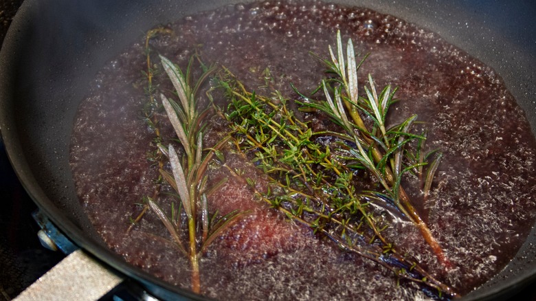 skillet deglazing with liquid and herbs