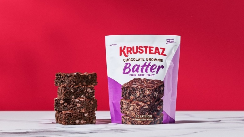 Stack of four brownies next to package of Krusteaz Chocolate Brownie Pour and Bake Batter