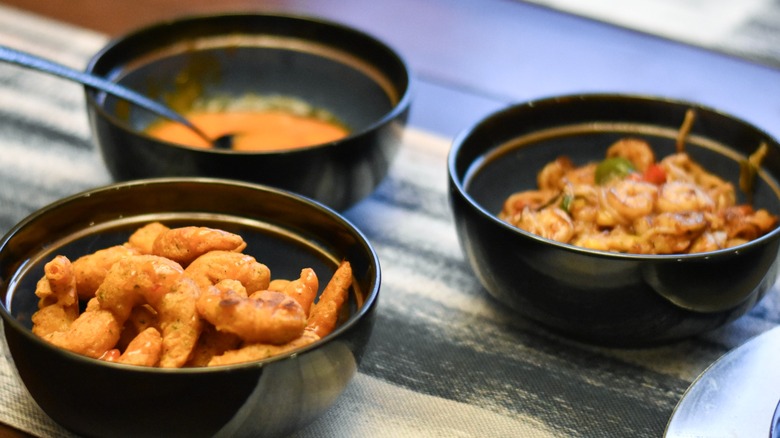Bowls of shrimp dishes and sauce served on a table
