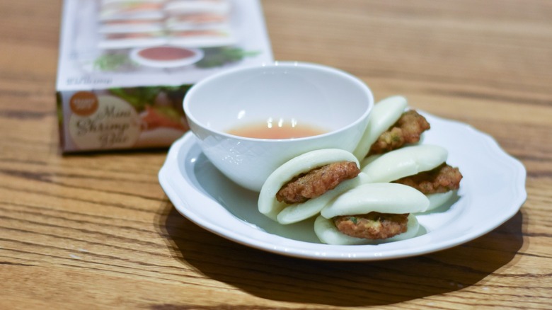 Four shrimp bao with sauce on a white plate