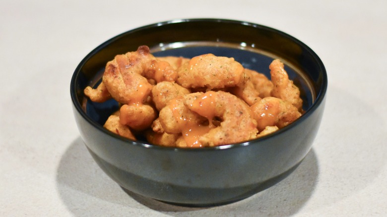 A black bowl with breaded shrimp and sauce