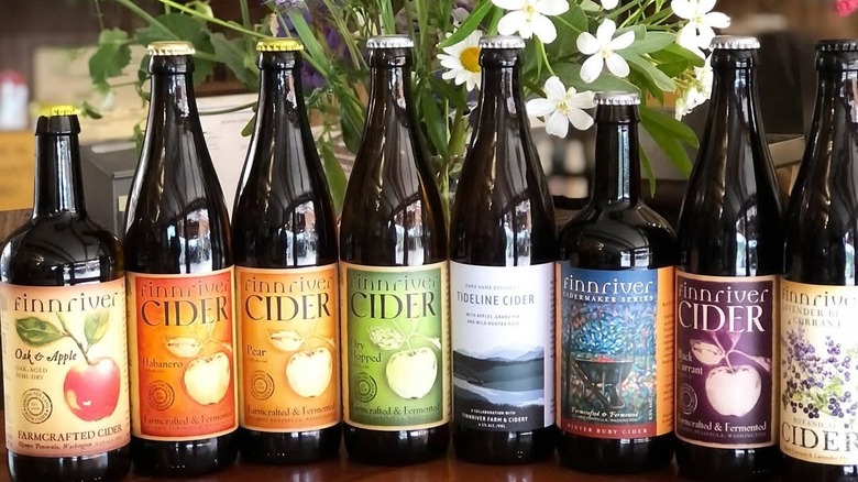 A row of cider bottles with flowers behind