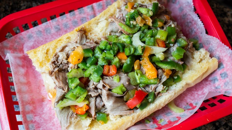 An Italian beef with peppers sits in a basket.