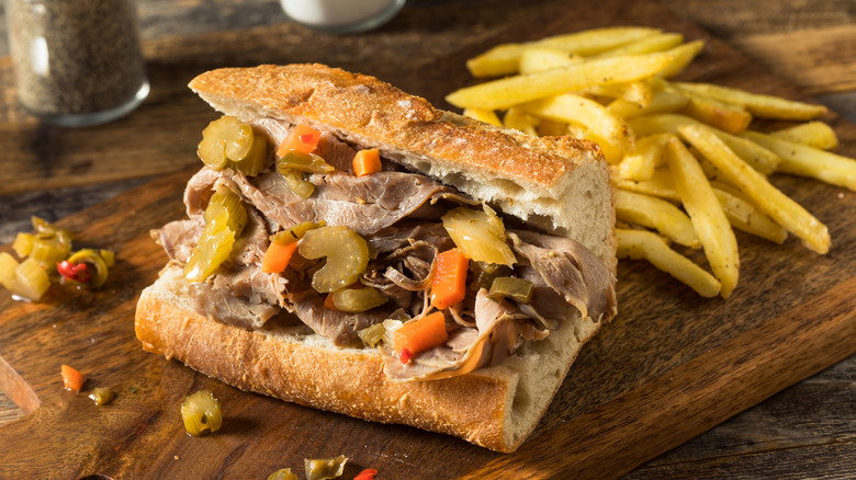 Italian beef sits on a table with french fries.