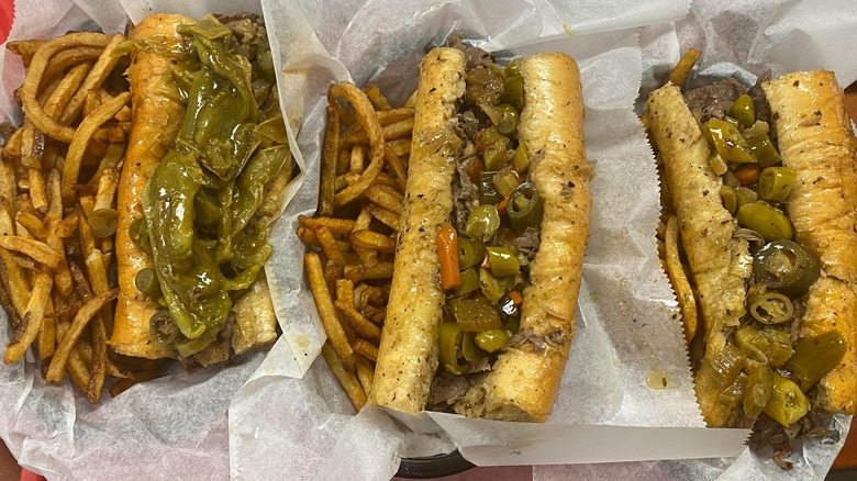 Three Italian beef sandwiches are on paper.