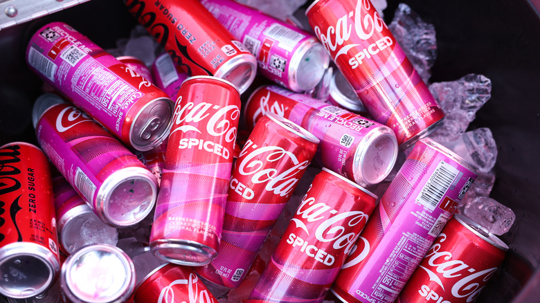 A pile of Coca-Cola Spiced cans of soda sitting on ice