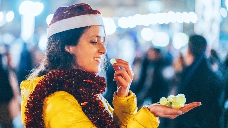 Woman in festive attire eating green grapes