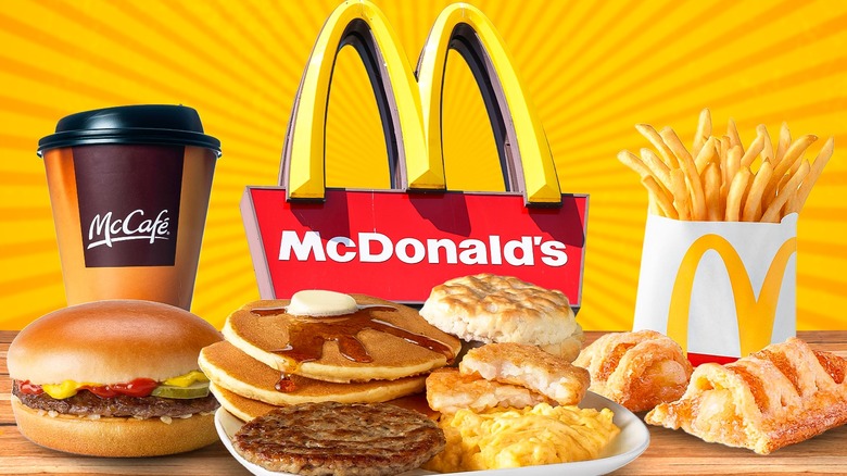 An image showing a McCafe cup with lid, fries, hamburger, split apple pie, and a breakfast combo from McDonald's in front of the golden arches and a yellow background