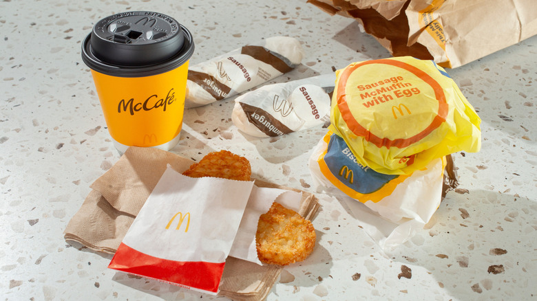 McDonald's breakfast combo meal on table, with two hash browns, coffee, and other items