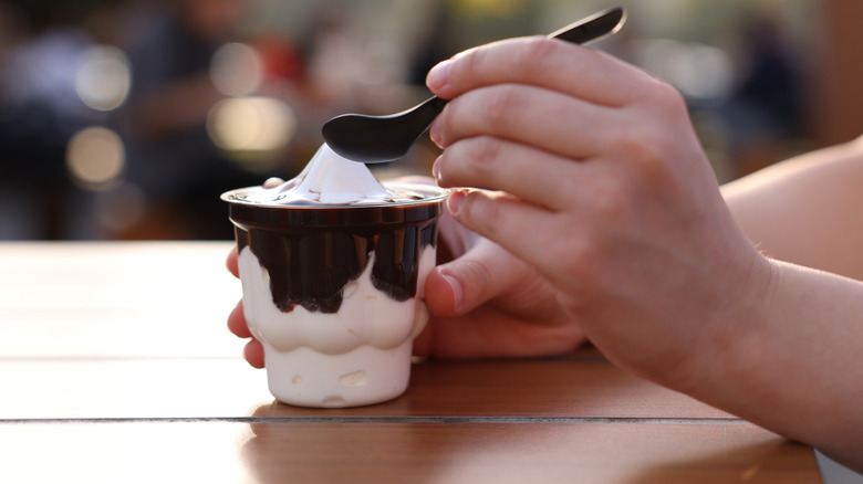 Woman's hand holding spoon near McDonald's chocolate sundae