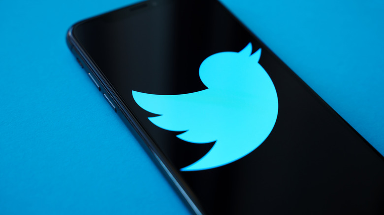 The old blue Twitter bird symbol on a black smartphone screen