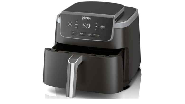 Ninja Air Fryer Pro 4-in-1 on wooden counter between a plate of chicken nuggets and a bowl of fries