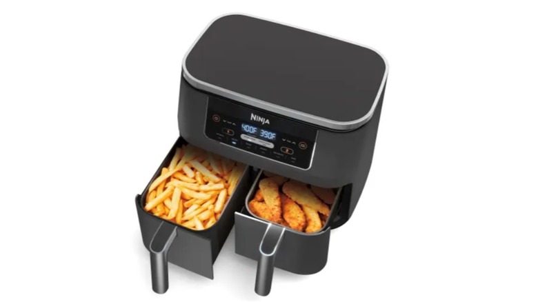 Ninja Foodi 8-Quart 6-in-1 DualZone 2-Basket Air Fryer on a kitchen island with a plate of fries and a plate of wings in front of it