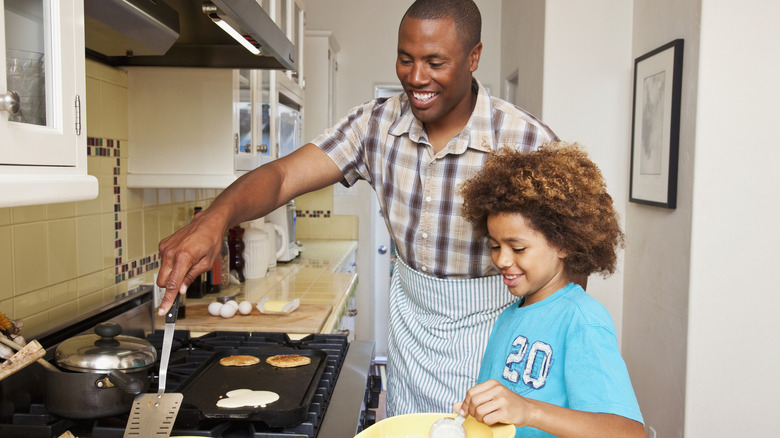 Dad and daughter cooking pancakes on griddle