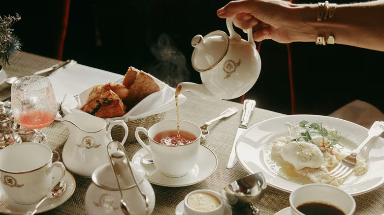 Hand pouring tea plus breakfast food on the Belmond Royal Scotsman