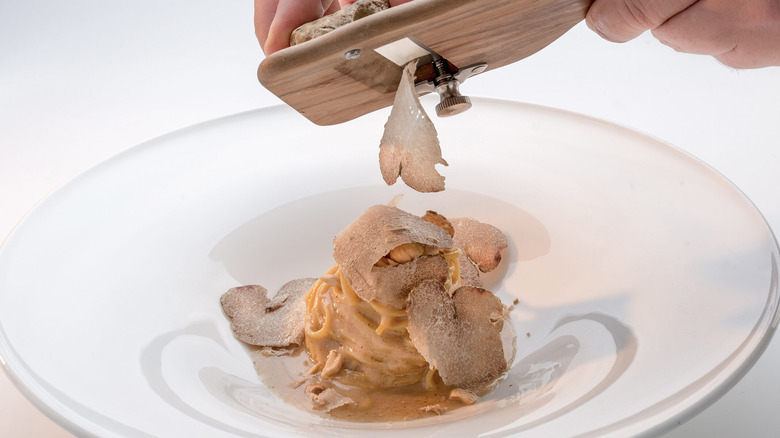 Hand shaving truffles on creamy pasta