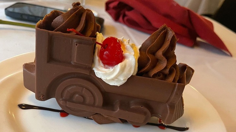 Train-themed chocolate dessert with Chantilly cream and a cherry