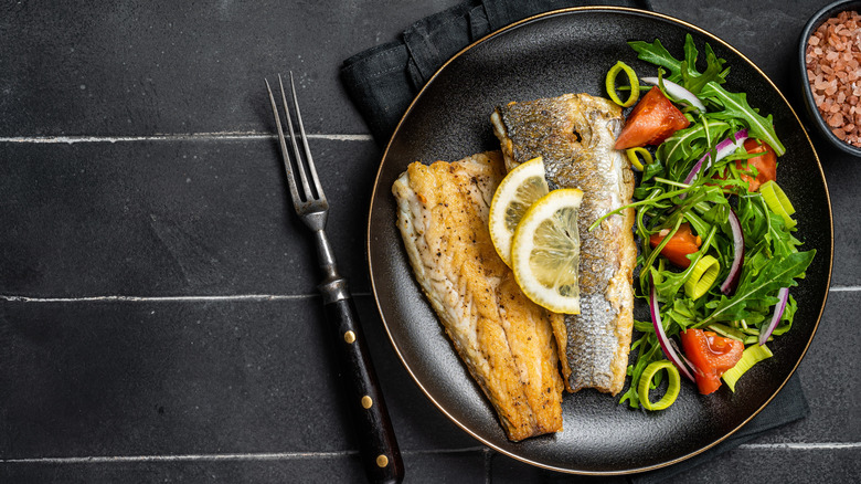 Fried branzino fish on a plate with salad