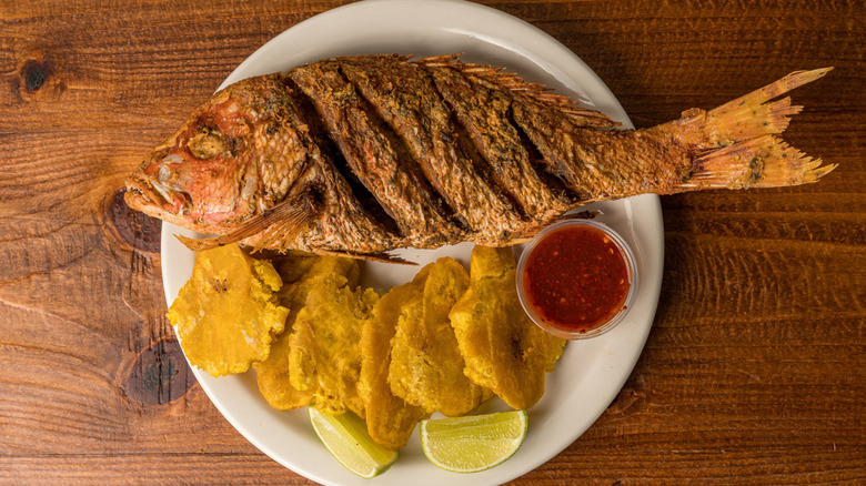 A fried red snapper on a plate with plaintains