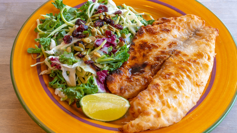 A plate of fried tilapia with salad