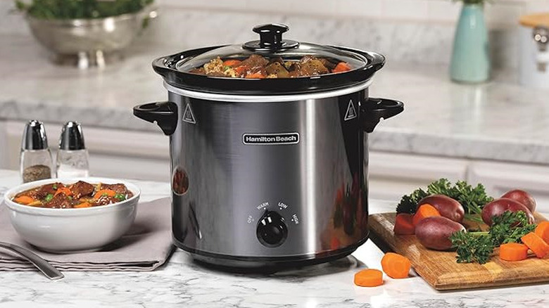 Hamilton Beach 4 Quart Round Slow Cooker on kitchen counter surrounded by dishes