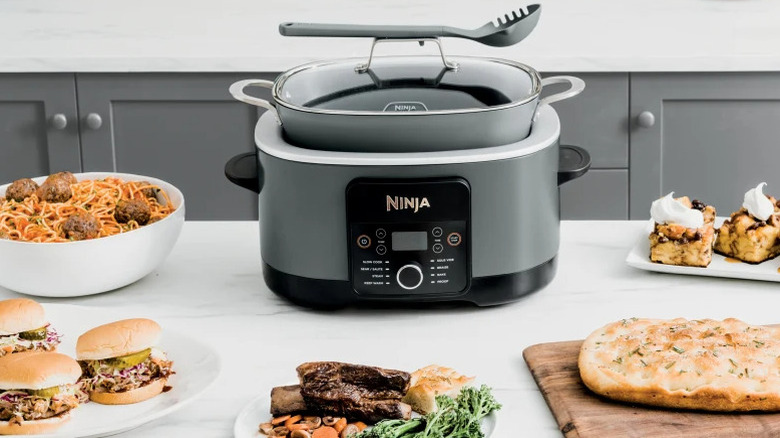 The Ninja Foodi PossibleCooker PRO on a counter surrounded by different dishes