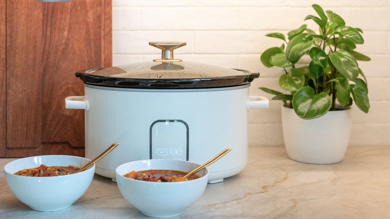 Drew Barrymore Touchscreen Slow Cooker on countertop with two bowls of chili