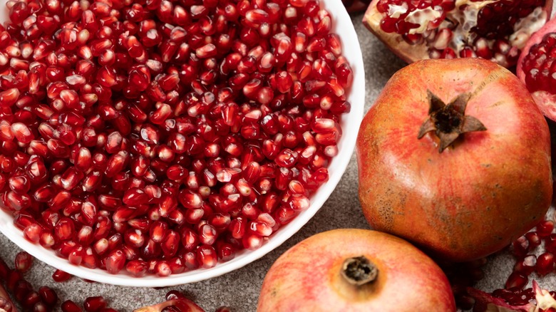 plate of pomegranate seeds and full pomegranate fruit