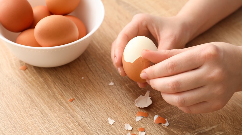hands peeling hard-boiled egg