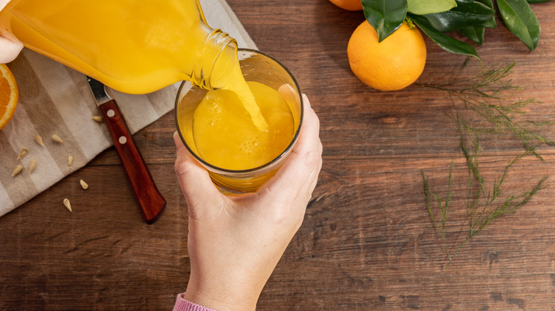 Person pouring orange juice