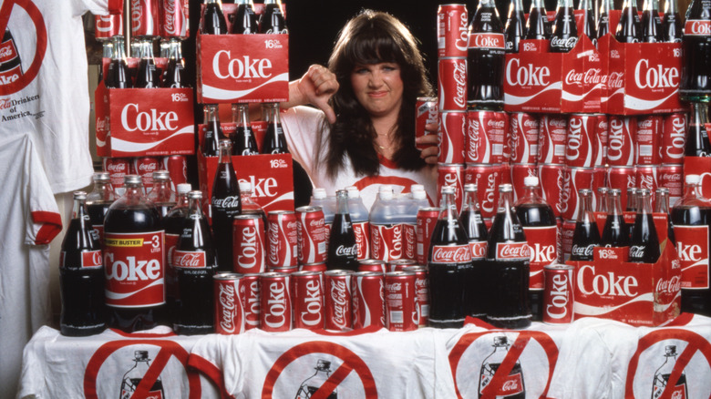 Woman surrounded by New Coke giving a thumbs down