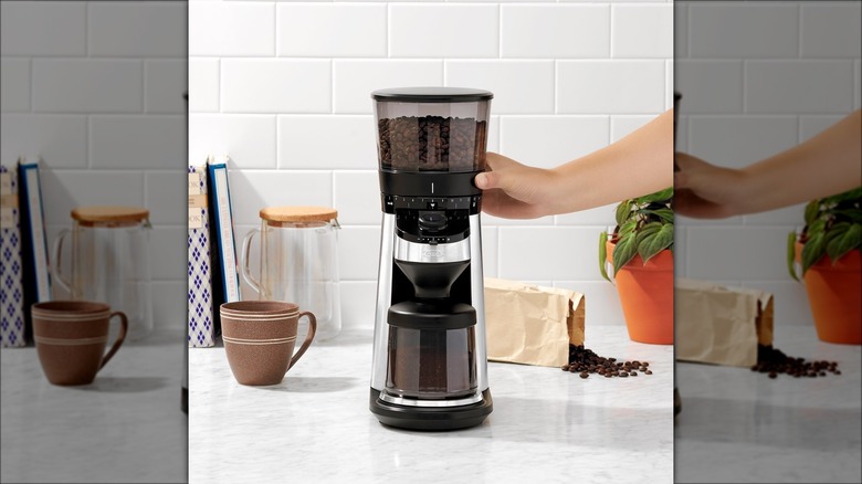 Hand touching OXO conical burr grinder