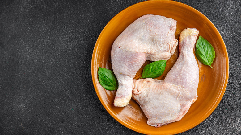 raw chicken leg quarters on plate
