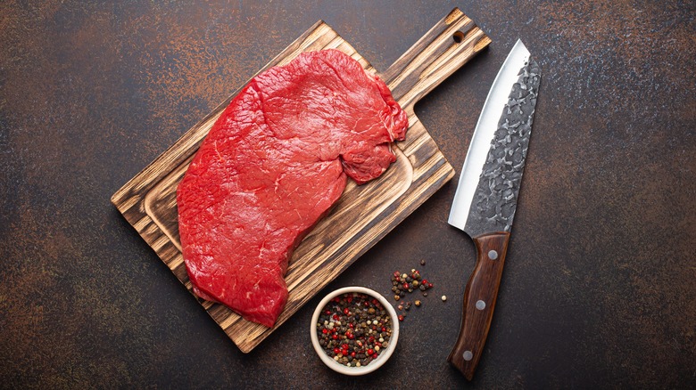 Top round steak, peppercorns, knife