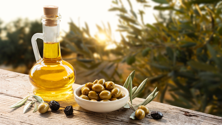 Bottle of olive oil and olives on outdoor table